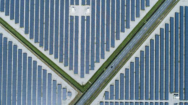 overhead view of a road cutting through solar panel fields